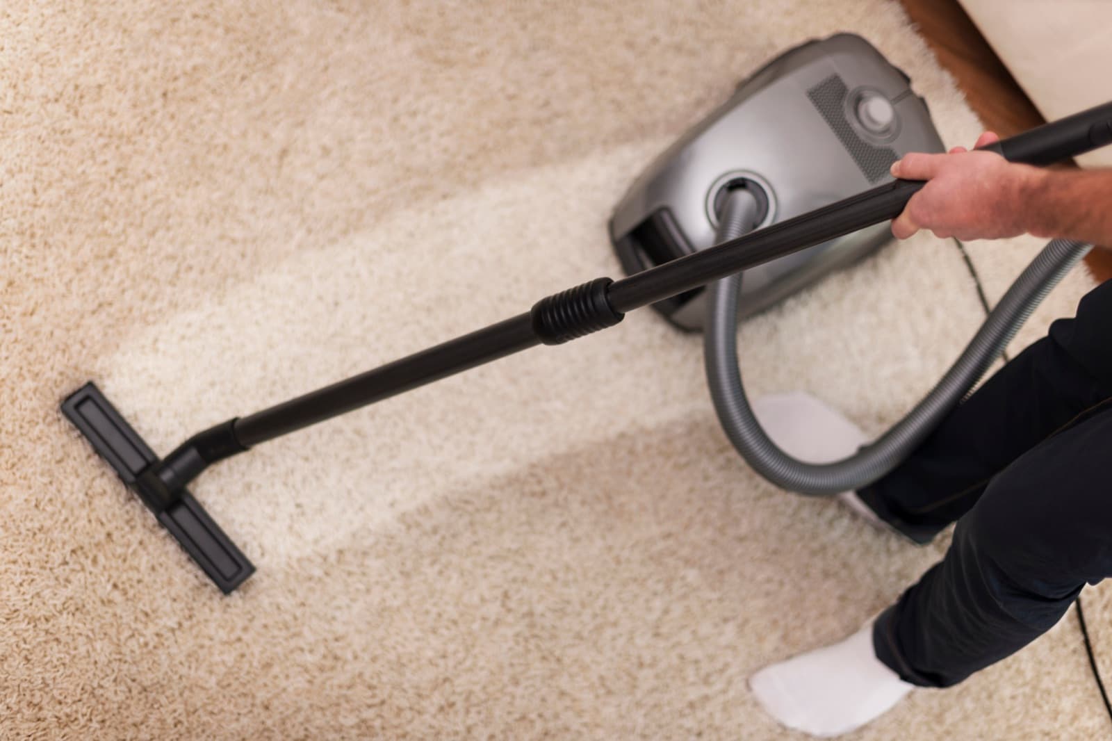 Commercial cleaner vacuuming carpet with professional equipment